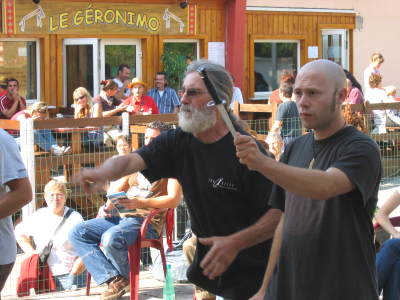 Knife throwing, with spectators on the tarrace in the background.